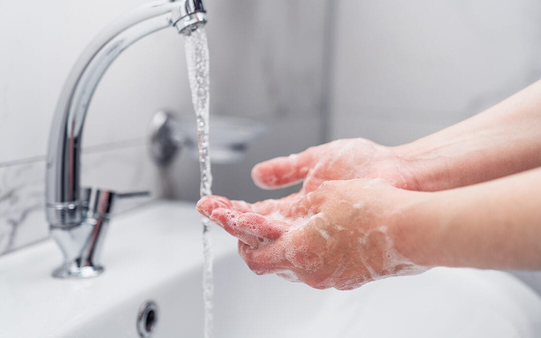 woman cleaning her hands with soap on faucet to protect from virus